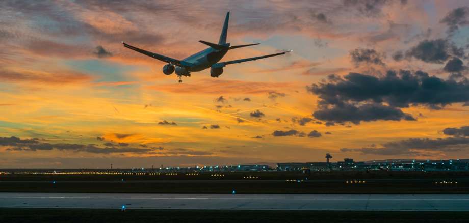 Ein Flugzeug landet am Frankfurter Flughafen vor bewölktem Himmel.