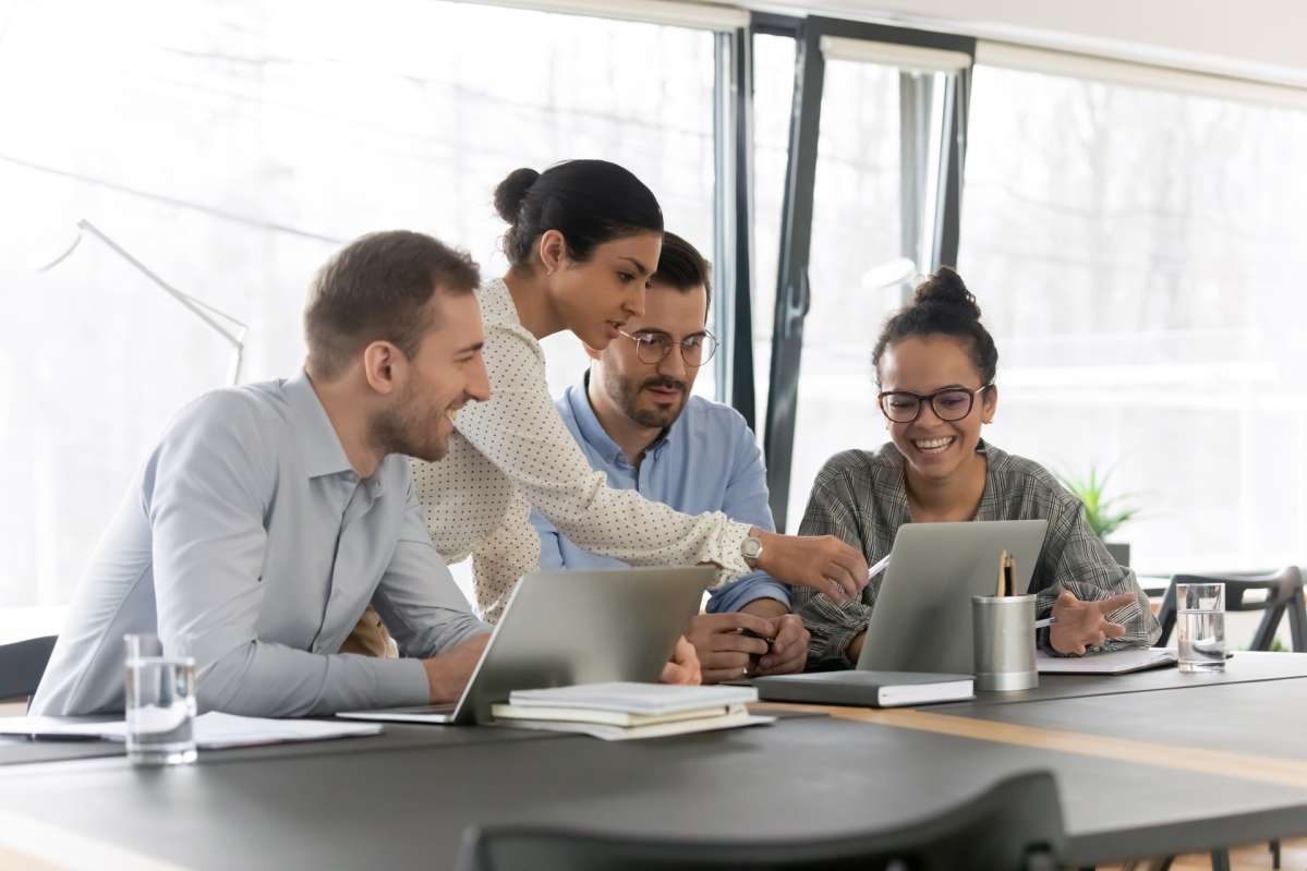 four people sitting in front of laptop four people sitting in front of laptop